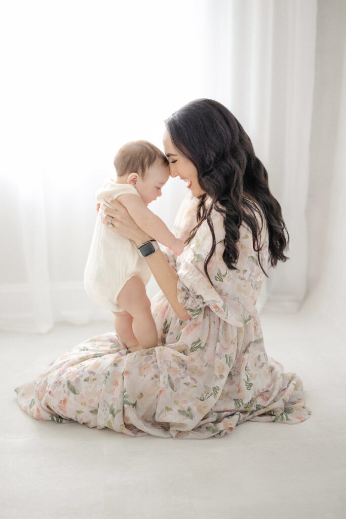 Baby boy and mom snuggling during a milestone session in natural studio light at a Tampa photography studio.