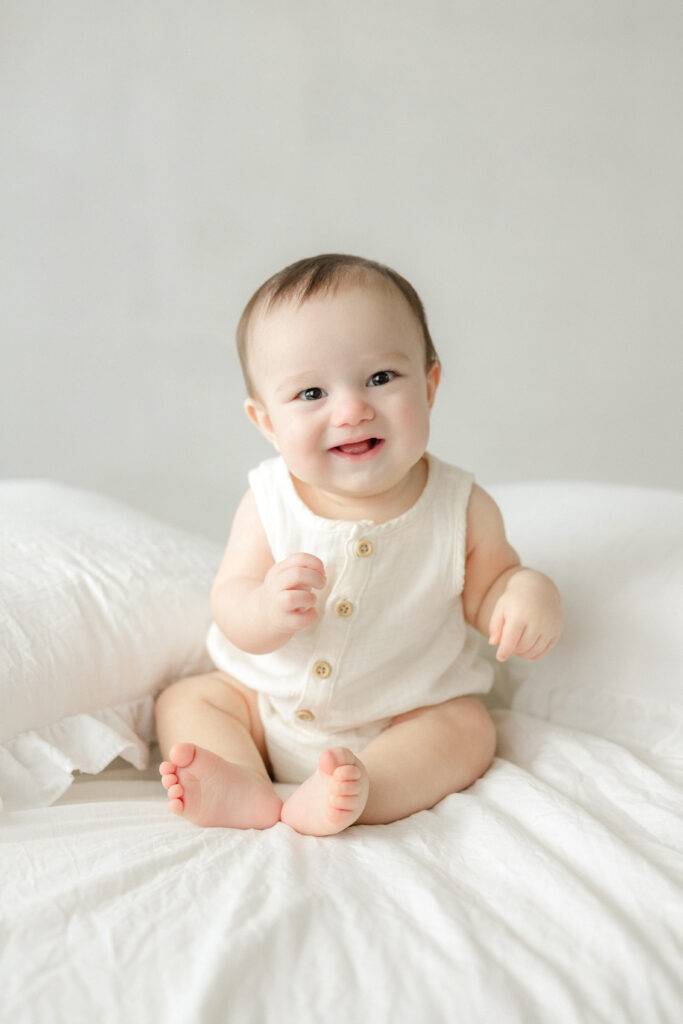 Baby boy sitting and smiling during a milestone session in natural studio light at a Tampa photography studio.