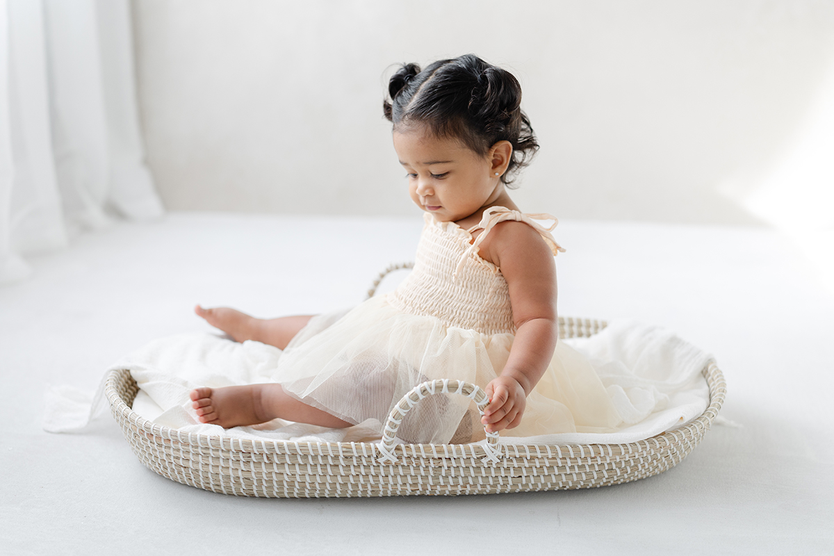 Baby girl in a tulle dress photographed in a natural light studio during a milestone portrait session in Tampa.